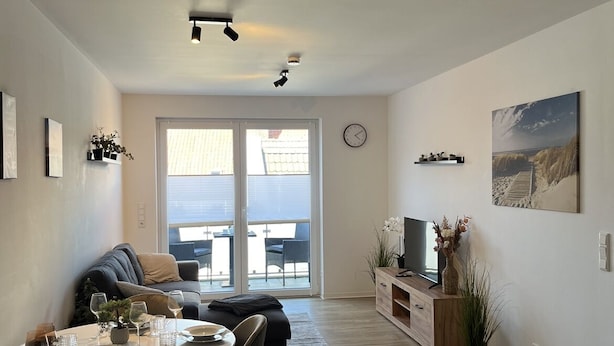 Ein modernes Wohnzimmer mit Essbereich, großen Fenstern und Blick ins Freie.