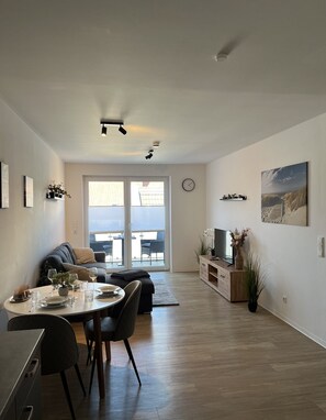 A modern living room with a dining area, large windows, and a view of the outdoors. - Wohnglück Leer-Altstadt (Leer (Ostfriesland))