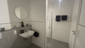 Ein modernes Badezimmer mit Waschbecken, Spiegel und Duschbereich.