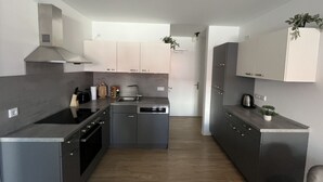 Eine moderne Küche mit grauen Schränken, einer Edelstahl-Dunstabzugshaube, einem Geschirrspüler und einem Kühlschrank.