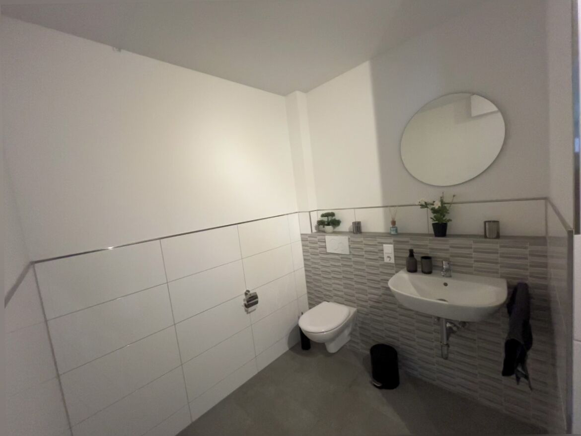 A modern bathroom with a white toilet, a sink, and a mirror.