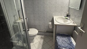 A bathroom with a glass shower enclosure, a toilet, a sink, and a mirror. - Cocoon Paris (Paris)