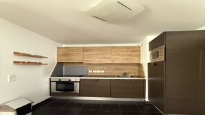 Une cuisine moderne avec des carreaux de couleur sombre, des appareils en acier inoxydable et des meubles de cuisine en bois.
