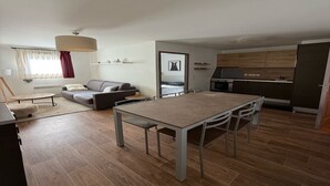 Un salon moderne comprenant un canapé, une table à manger et un coin cuisine avec des meubles en bois.