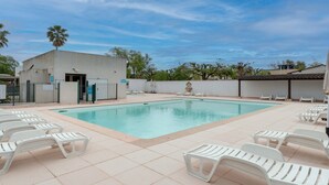 Ein Schwimmbecken mit Liegestühlen und ein Gebäude mit Tür und Fenstern.