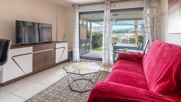 Ein modernes Wohnzimmer mit Fernseher, einem roten Sofa und einem Glastisch.
