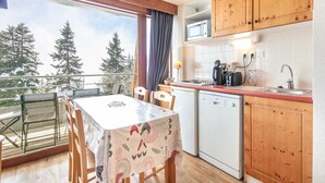 A kitchen with wooden cabinets, a microwave, a sink, and a dining table with chairs. - Apartment in Chamrousse near Ski Slopes (Chamrousse)
