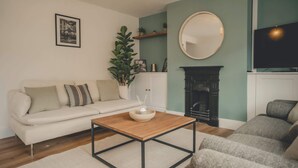 A living room with a sofa, a coffee table, a fireplace, and a television. - Modern 3BR Home with Stunning Garden | Banbury Stay (Banbury)