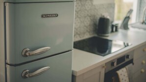 A kitchen with a vintage blue refrigerator, a modern stove, and patterned backsplash. - Modern 3BR Home with Stunning Garden | Banbury Stay (Banbury)