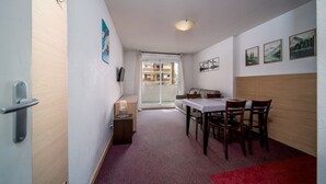 A hotel room with a dining area, a sofa, a table, and a window with a view of a balcony. - Apartment in Allos near Ski Resort (Allos)