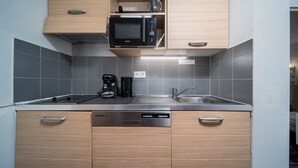 A modern kitchen with wooden cabinets, a built-in microwave, a coffee maker, and a dishwasher. - Apartment in Allos near Ski Resort (Allos)