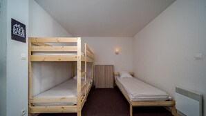 A dormitory room with bunk beds, a single bed, a wall-mounted light, and a radiator. - Apartment in Allos near Ski Resort (Allos)