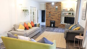Relax in this stylish living room with a brick fireplace, flat-screen TV, and comfortable seating areas.