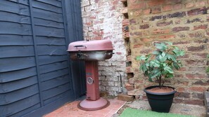 Enjoy outdoor cooking and relaxation in this patio with a barbecue grill and lush greenery.