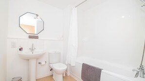 Et badeværelse med hvid vask, toilet og badekar.