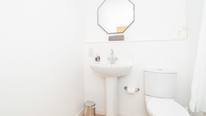 Ein Badezimmer mit einem weißen Waschbecken, einer Toilette und einem Spiegel.