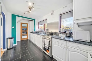 A modern kitchen with white cabinets, a stove, and a microwave.