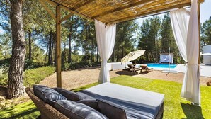 A covered outdoor seating area with a pool and a view of the surrounding forest. - My Rental Homes - Villa Floresta private pool and large garden (Sant Antoni De Portmany)