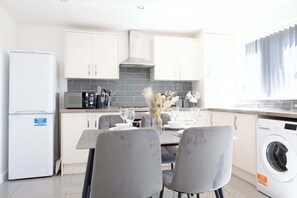 A modern kitchen with white cabinets, a built-in microwave, and a washing machine.