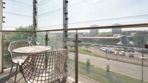 A balcony with a glass railing, two chairs, and a table. - Elegant 1BR – Sheffield City Centre (South Yorkshire)