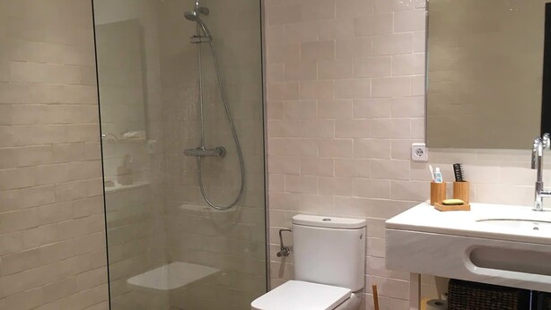 Une salle de bain moderne avec une douche à parois de verre, des toilettes et un lavabo équipé de produits de toilette.