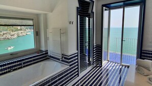 Ein modernes Badezimmer mit einer Badewanne, einer Dusche und Meerblick.
