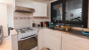 A compact kitchen with a gas stove, white cabinets, a window with blinds, and a tiled backsplash. - Amedei Apartment: 2 suites {10 m from Ponte Vecchio} (Firenze)