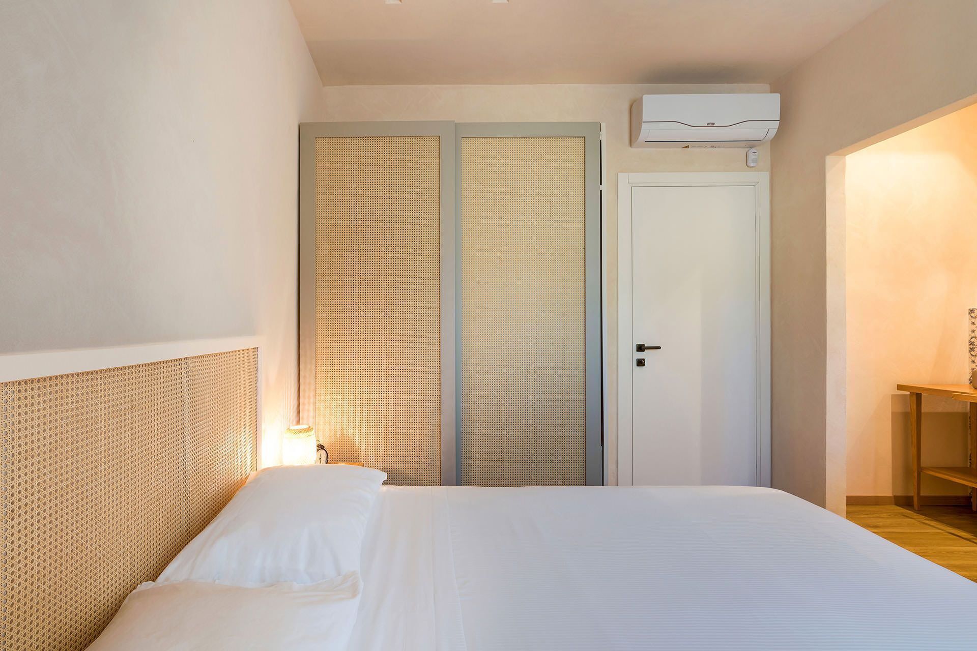 A bedroom with a bed, a wardrobe, and a bedside table.