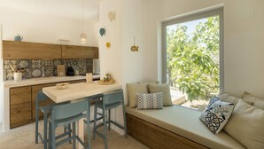 Eine moderne Küche mit Holztischplatte, ein Essbereich mit blauen Stühlen und eine Fensterbank mit Kissen.