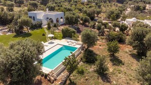 Eine weiße Villa mit Swimmingpool, umgeben von Olivenbäumen und einem Garten.