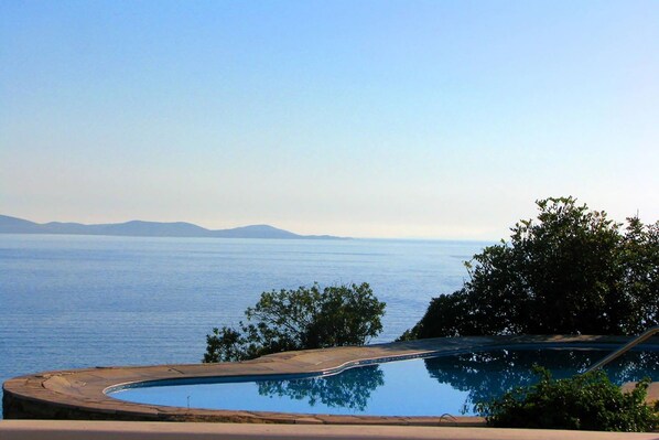 A swimming pool with a view of the sea and distant mountains.