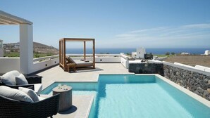 Un espace piscine aménagé sur le toit, offrant une vue dégagée sur la mer, avec un fauteuil de relaxation et une petite table avec des verres.