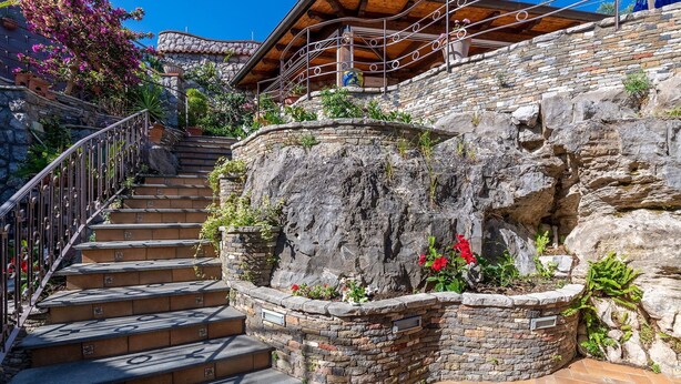 Una escalera de piedra con barandales de metal que lleva a un edificio de madera con un balcón.