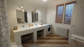 Ein Badezimmer mit zwei Waschbecken, einem Spiegel, einer Waschmaschine und einer Heizung.