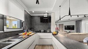 A modern kitchen with a central island, a built-in oven, and a large window.