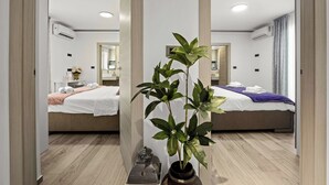A modern hotel room with a large mirror, two beds, a potted plant, and a small table with a decorative item.