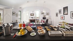 Cozinha moderna com área de refeições, apresentando um farto café da manhã com frutas, doces e bebidas.