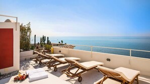 Terraço no telhado com espreguiçadeiras e vista para o mar.