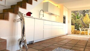 Una cocina moderna con armarios blancos, un grifo de acero inoxidable y un electrodoméstico rojo.