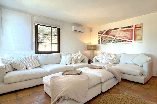 Una sala de estar con un sofá blanco, una mesa de centro y una lámpara de pie.