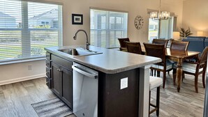 Una cucina moderna con isola centrale, elettrodomestici in acciaio inossidabile e illuminazione a sospensione.