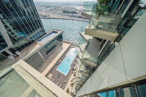 Un immeuble de grande hauteur doté d’une piscine sur le toit, de garde-corps en verre et offrant une vue sur une rivière.