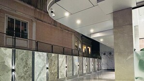 A spacious indoor corridor with a marble floor, a curved ceiling, and a glass wall on one side.