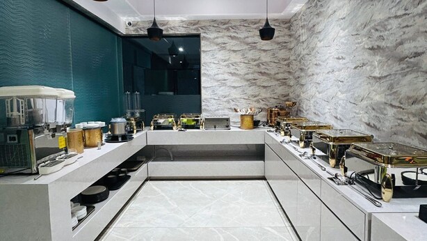 A modern kitchen with marble countertops, pendant lighting, and a central island.