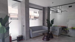 A modern lobby with a grey sofa, a glass partition, and a coffee table.