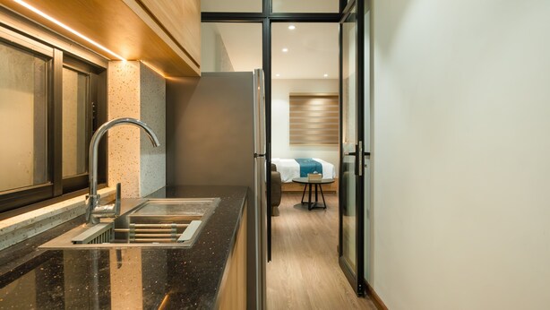 Eine moderne Küche mit einem Edelstahl-Kühlschrank, einem Waschbecken mit Armatur und einer Holzausziehtafel.
