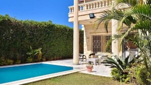 A large house with a swimming pool, a covered patio, and a well-maintained garden.