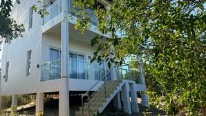 A modern two-story building with a glass balcony and a staircase leading to the entrance.