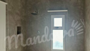 A bathroom with a shower, a window, and a towel rack.