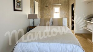A bedroom with a large bed, a bedside table with a lamp, and a wardrobe.